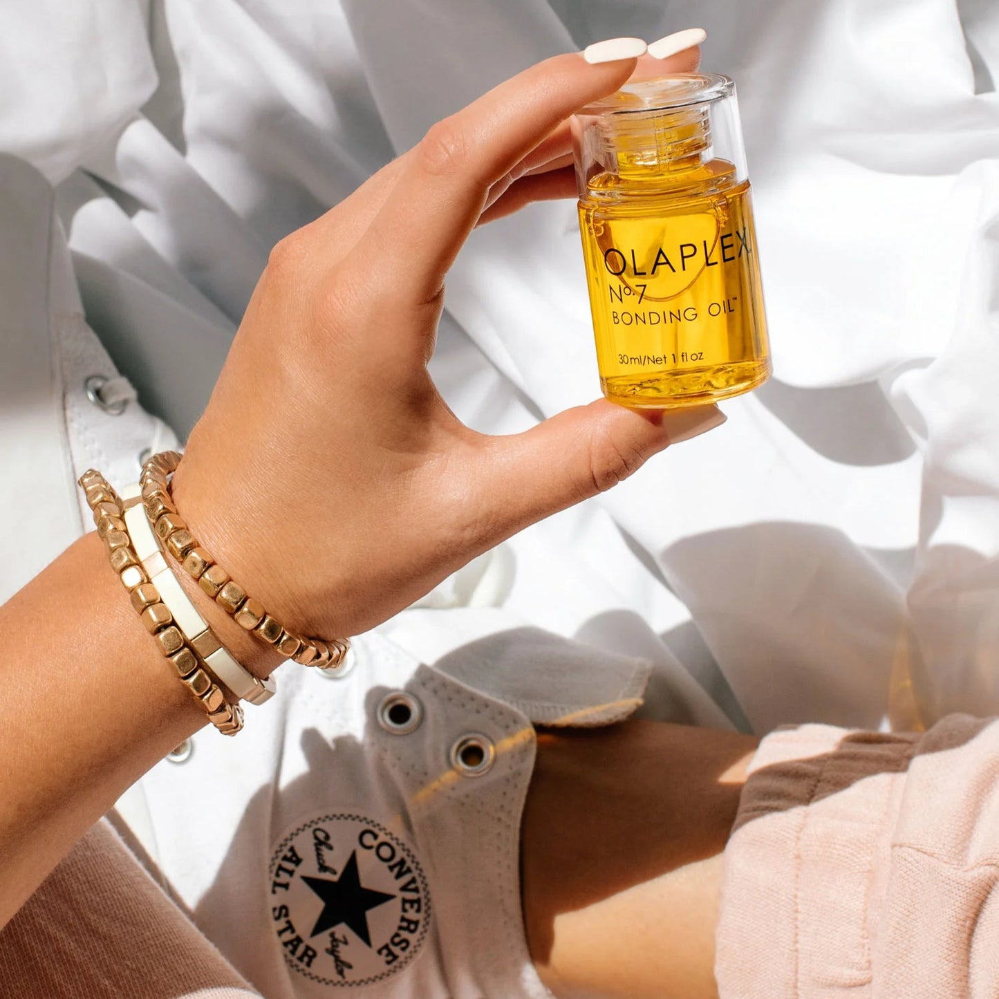 model holding Olaplex Oil No 7 bottle